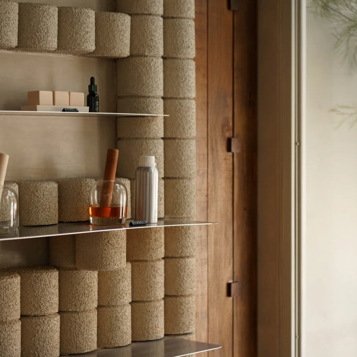 Shelves with cylindrical containers against a textured wall.