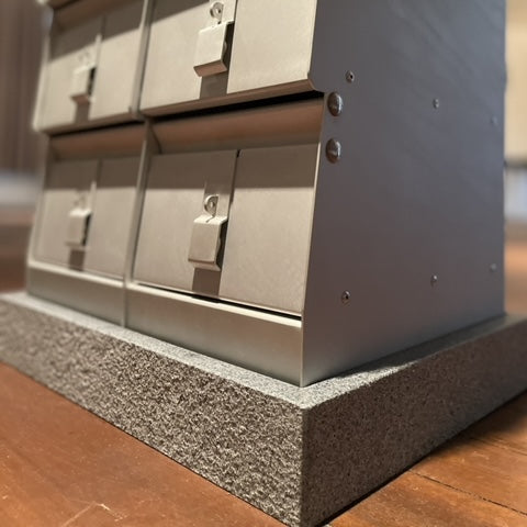 Metallic mailbox system on a wooden floor with a blurred background