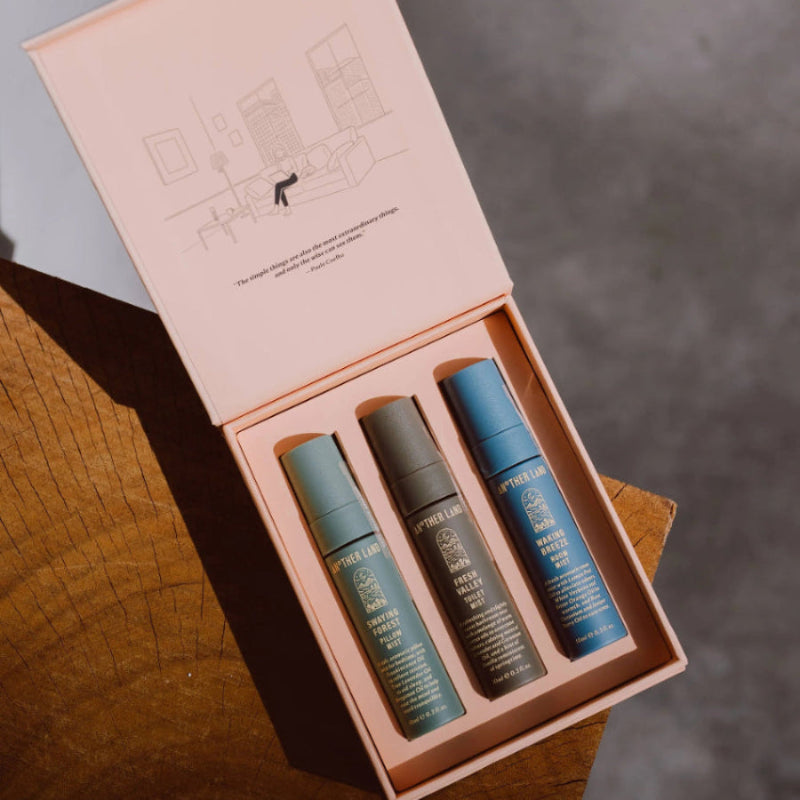 Three small bottles in a pink box on a wooden surface with a blurred background