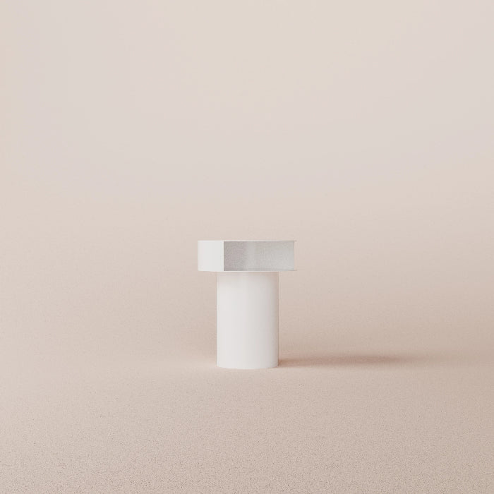 White cylindrical object with a metallic top on a beige background