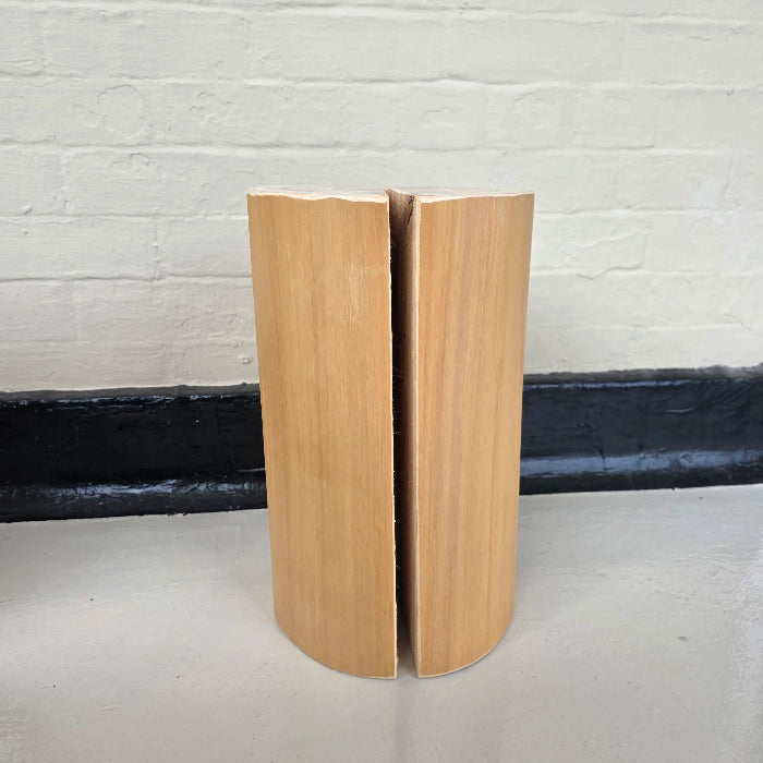 Solid wooden cedar block on a white surface with a white brick wall background